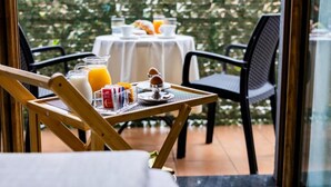 A dining table set with breakfast items, including orange juice, a pitcher, and a cup, with a view of greenery outside. - Il Principe Resort (Agerola)