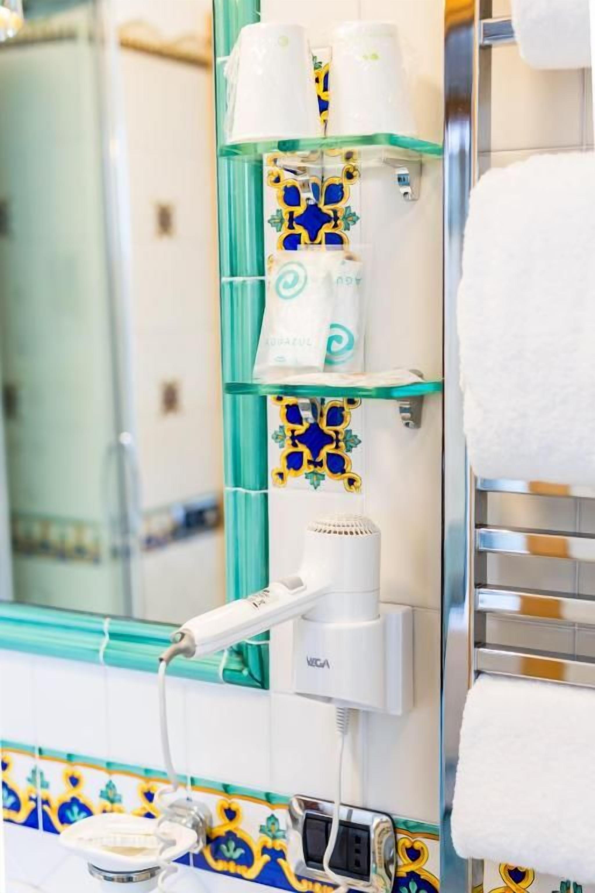 Une salle de bain avec un miroir, un porte-serviettes et un sèche-cheveux posé sur une étagère.