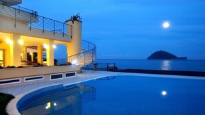 A modern building with a pool and a view of the sea at dusk. - Residence Sole (Albenga)
