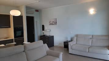 A modern living room with two sofas, a dining area with a table and chairs, and a kitchen with an oven.
