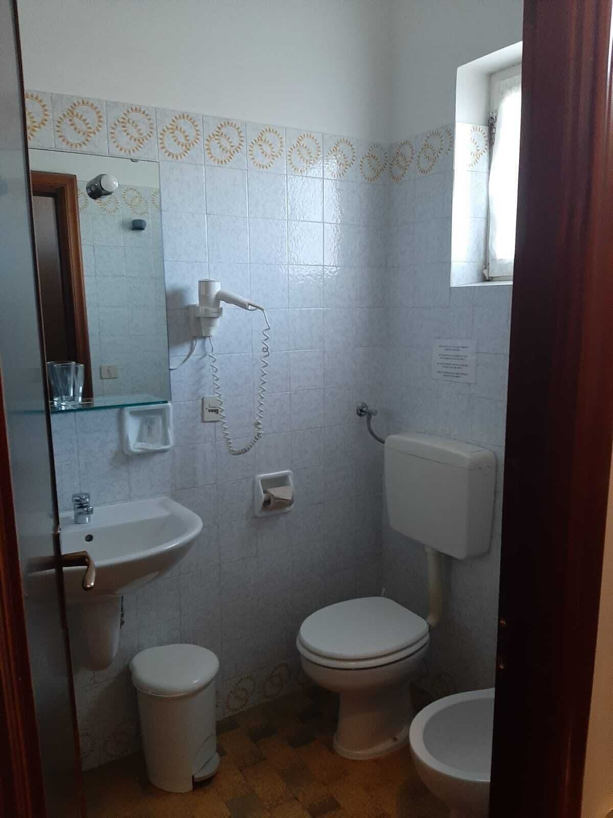 Une petite salle de bain avec un lavabo, deux toilettes et un miroir.