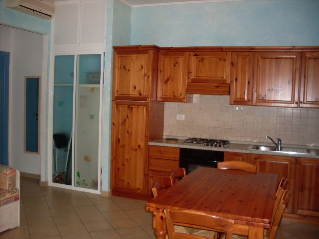 A kitchen with wooden cabinets, a dining table, and a stove.