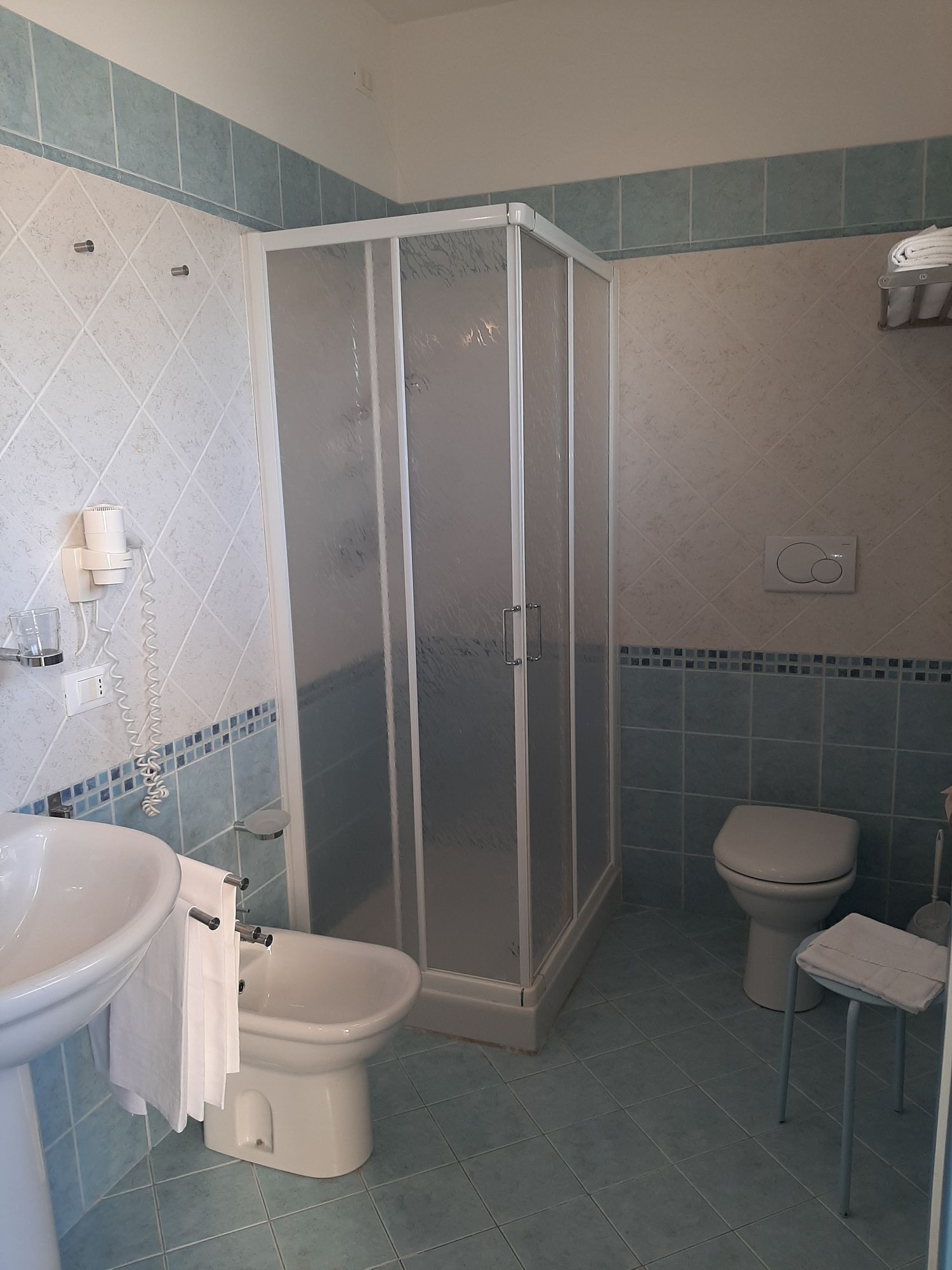 Ein Badezimmer mit Duschkabine, Toilette, Bidet und Waschbecken.