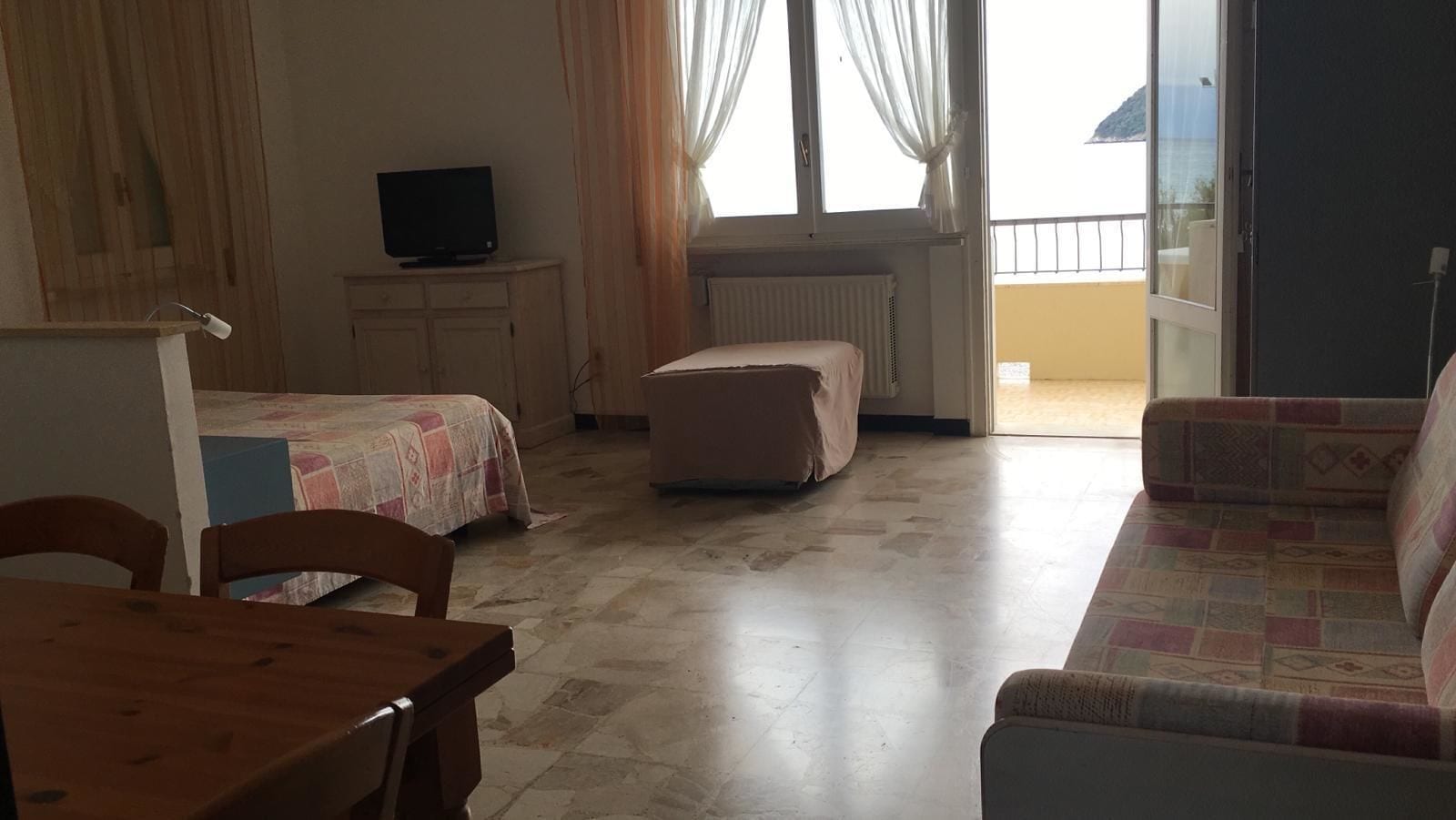 A room with a bed, a sofa, a table, and a television.