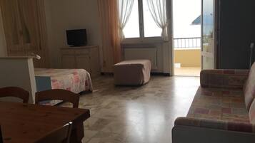 A room with a bed, a sofa, a table, and a television.
