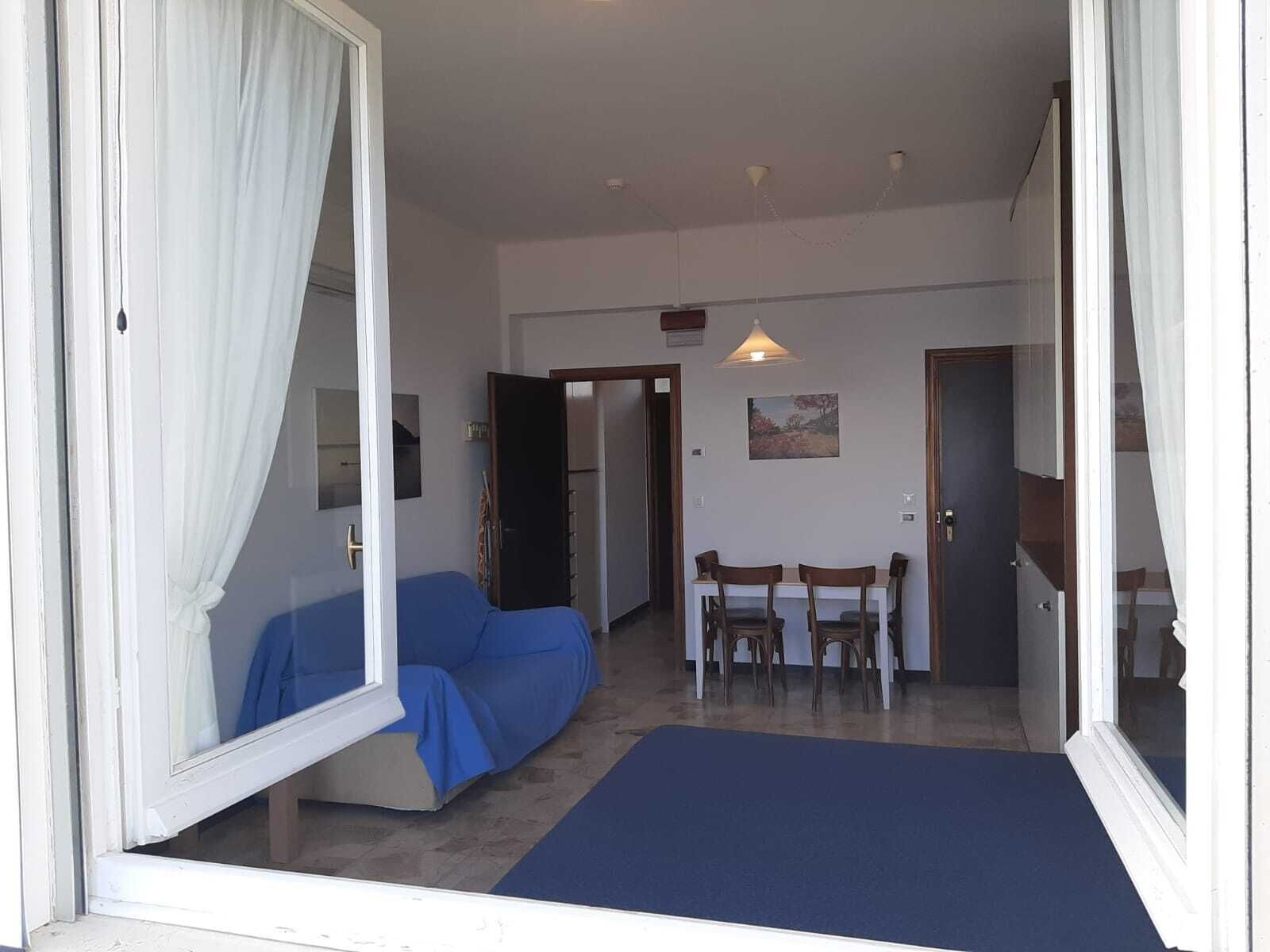 A room with a bed, a dining table with chairs, and a door leading to another room.