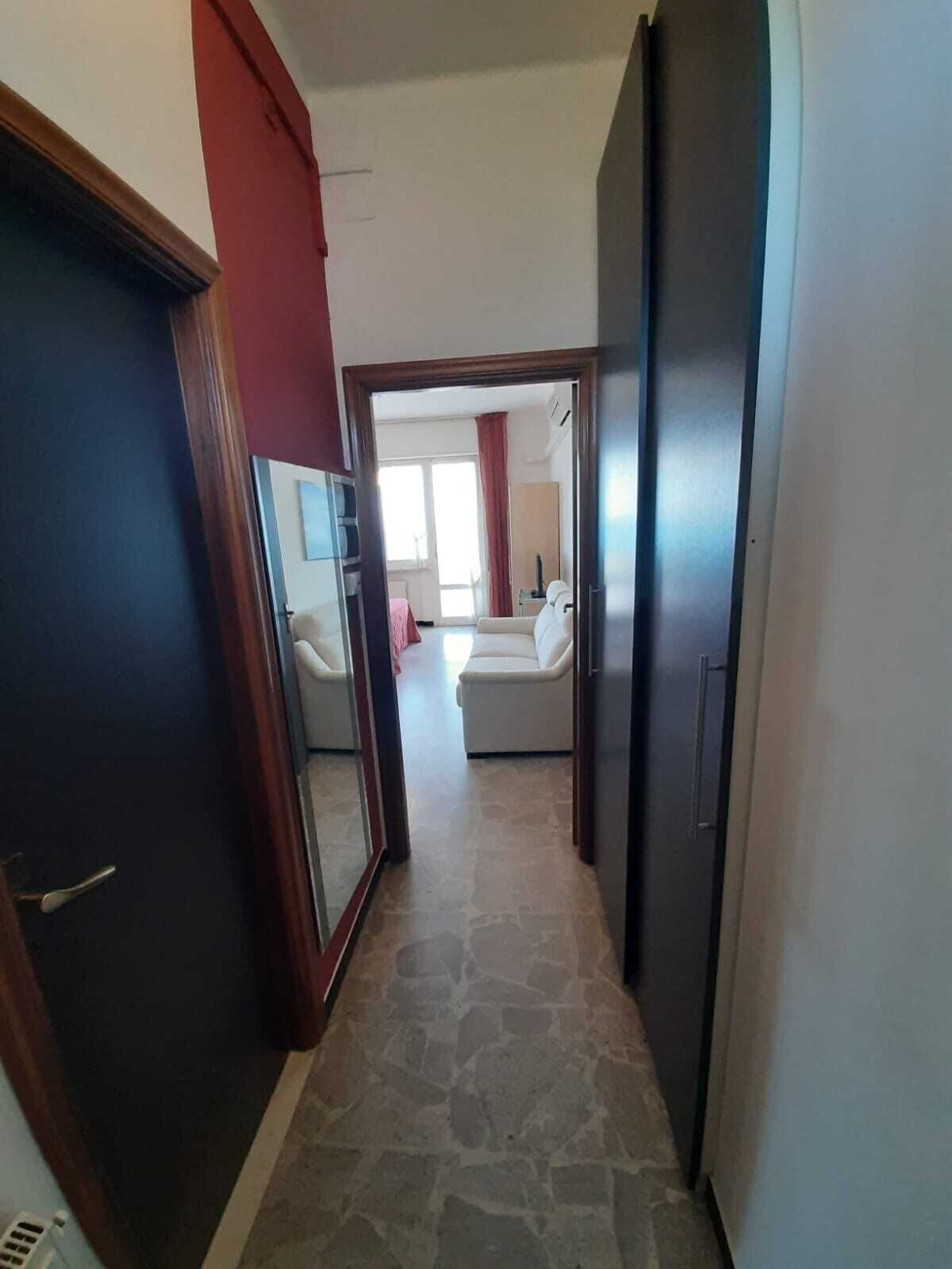 Un couloir dallé de pierres mène à une chambre à coucher qui contient un lit et une fenêtre.