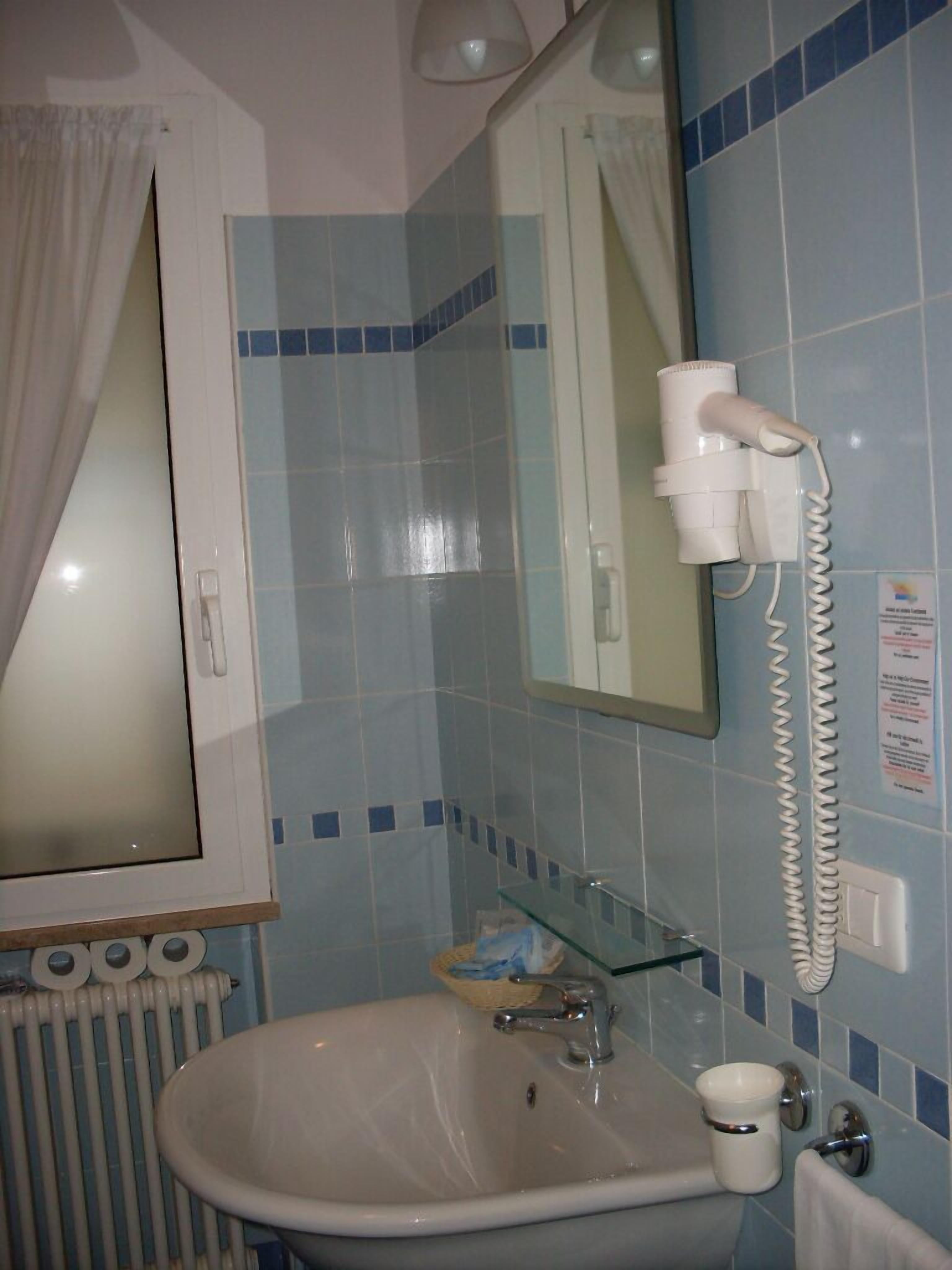 Un baño con lavabo, espejo y secador de pelo.