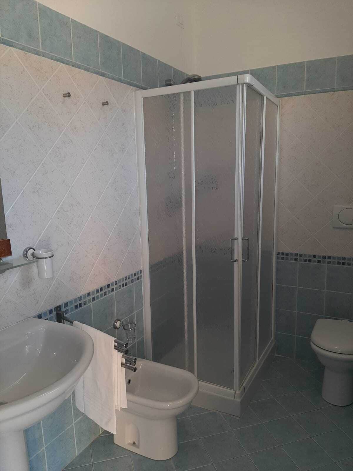 A bathroom with a shower enclosure, a toilet, and a sink.