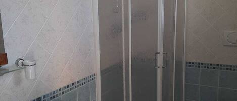 Un baño con cabina de ducha, inodoro y lavamanos.
