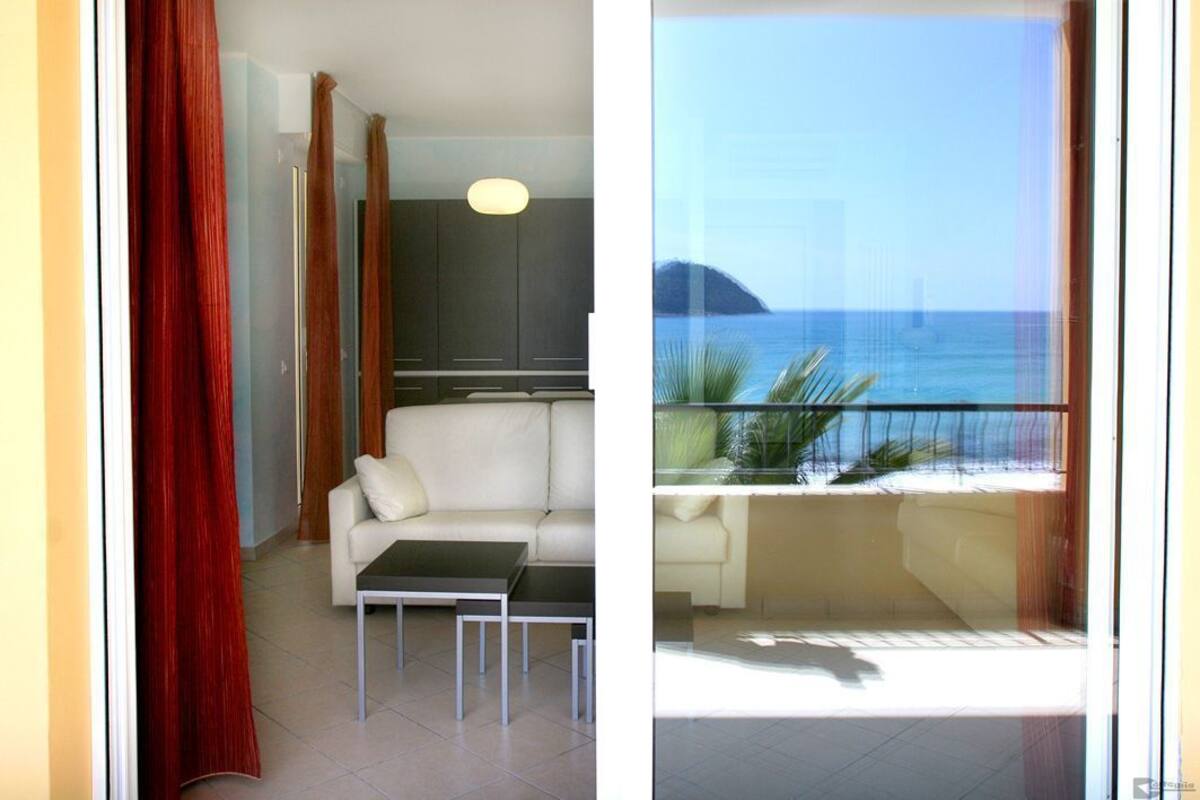 A living area with a sofa, a coffee table, and a view of the sea through a balcony.