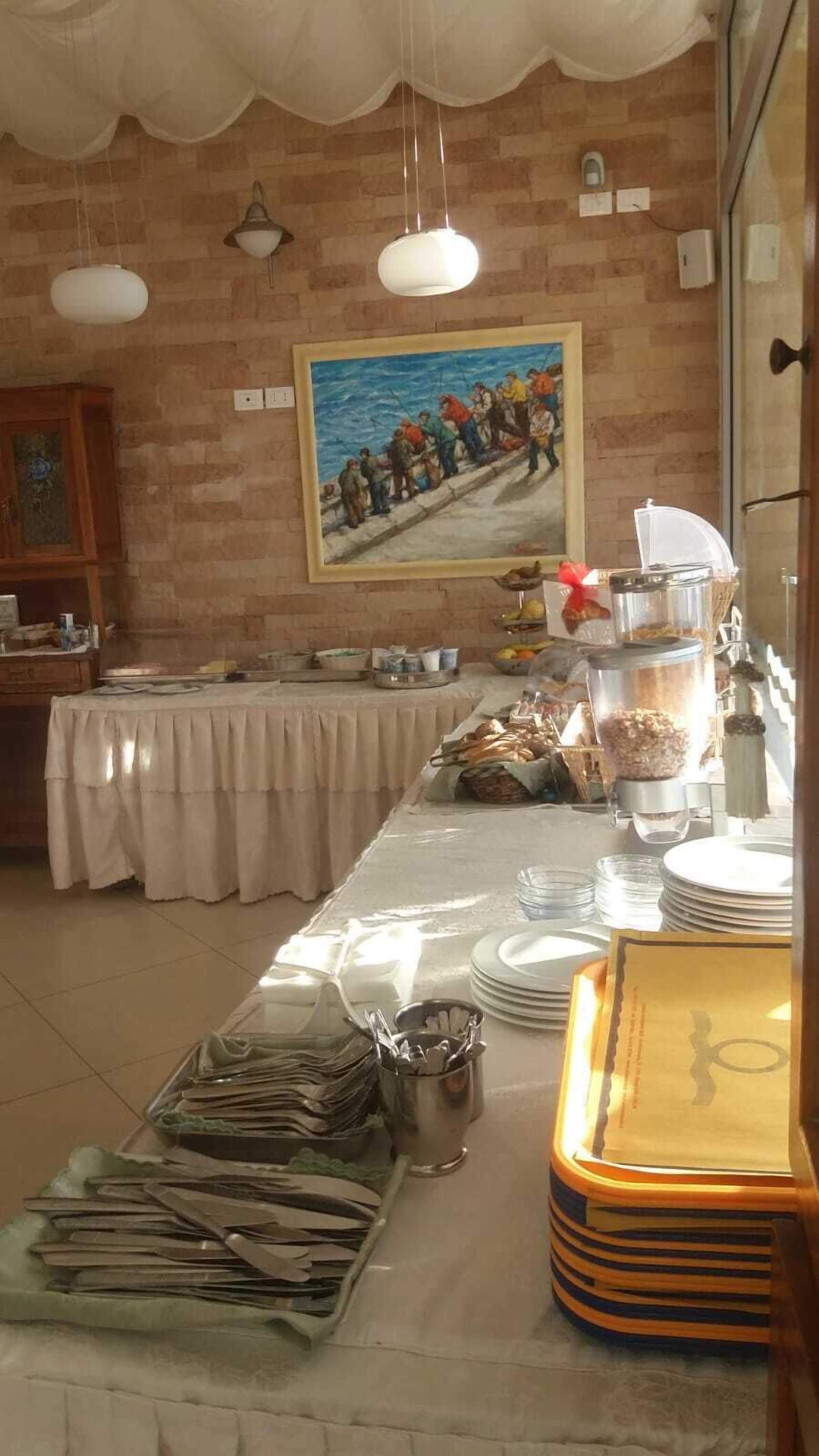 Un buffet disposé sur une longue table, avec des récipients contenant de la nourriture et un tableau accroché au mur.