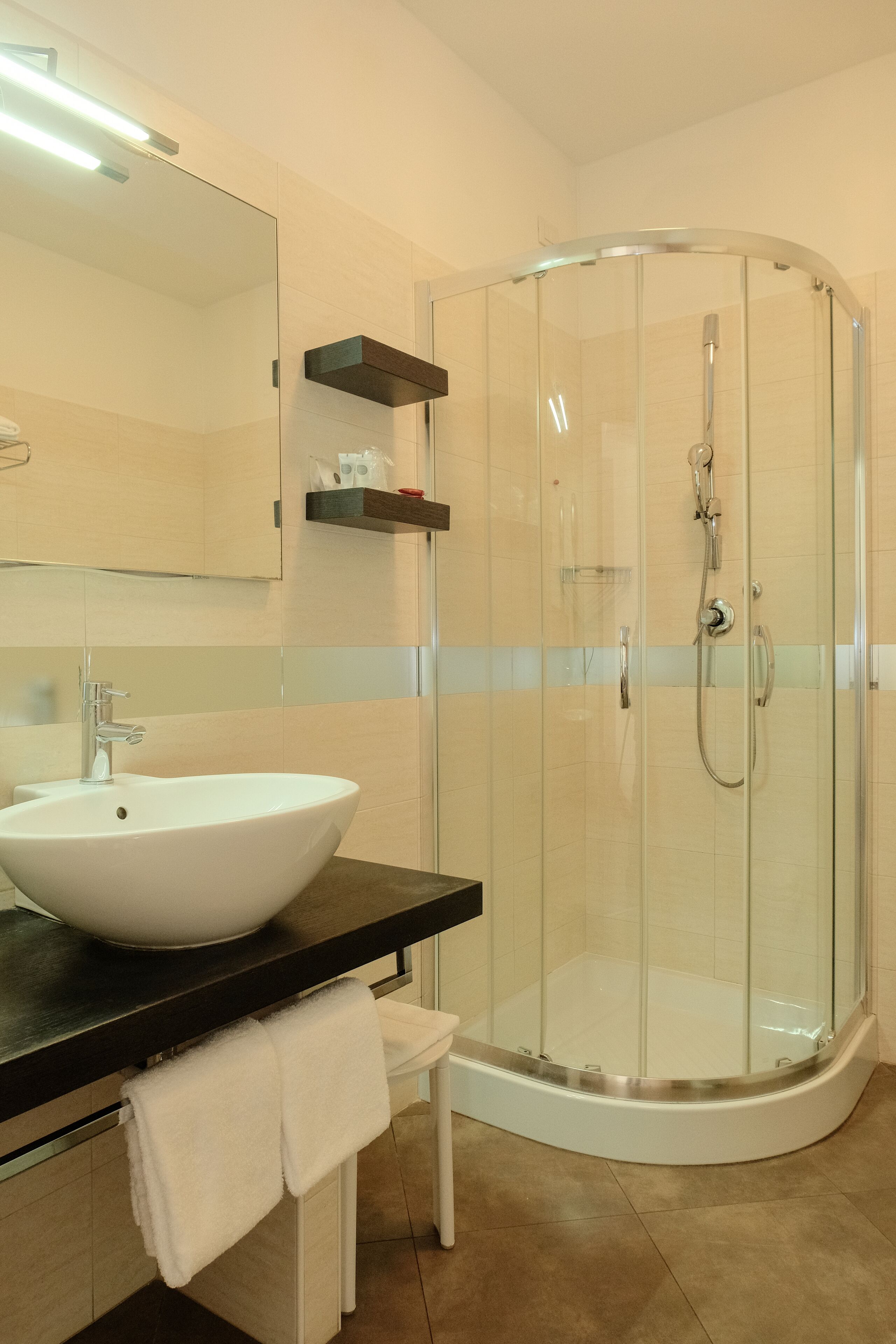 A modern bathroom with a glass-enclosed shower, a white sink, and a mirror above it.