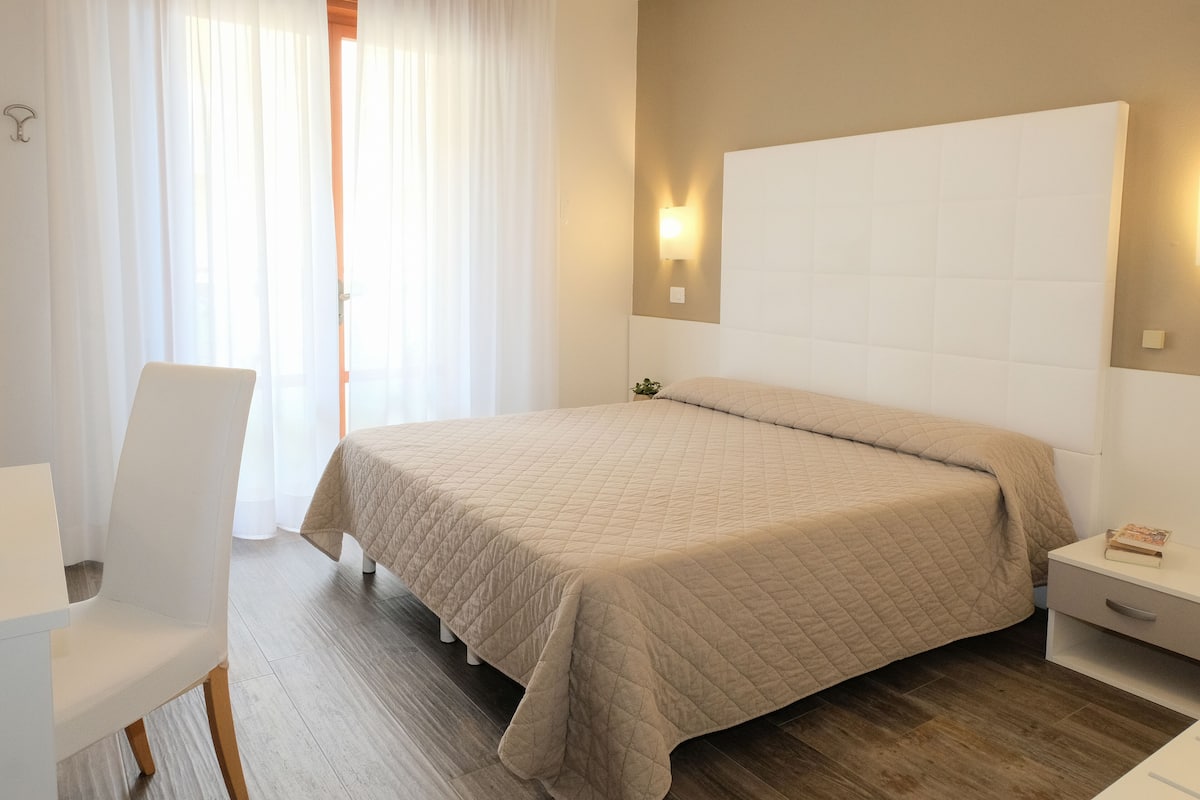 Ein Schlafzimmer mit einem Bett, einem Sessel, einem Nachttisch und einem Beistelltisch.