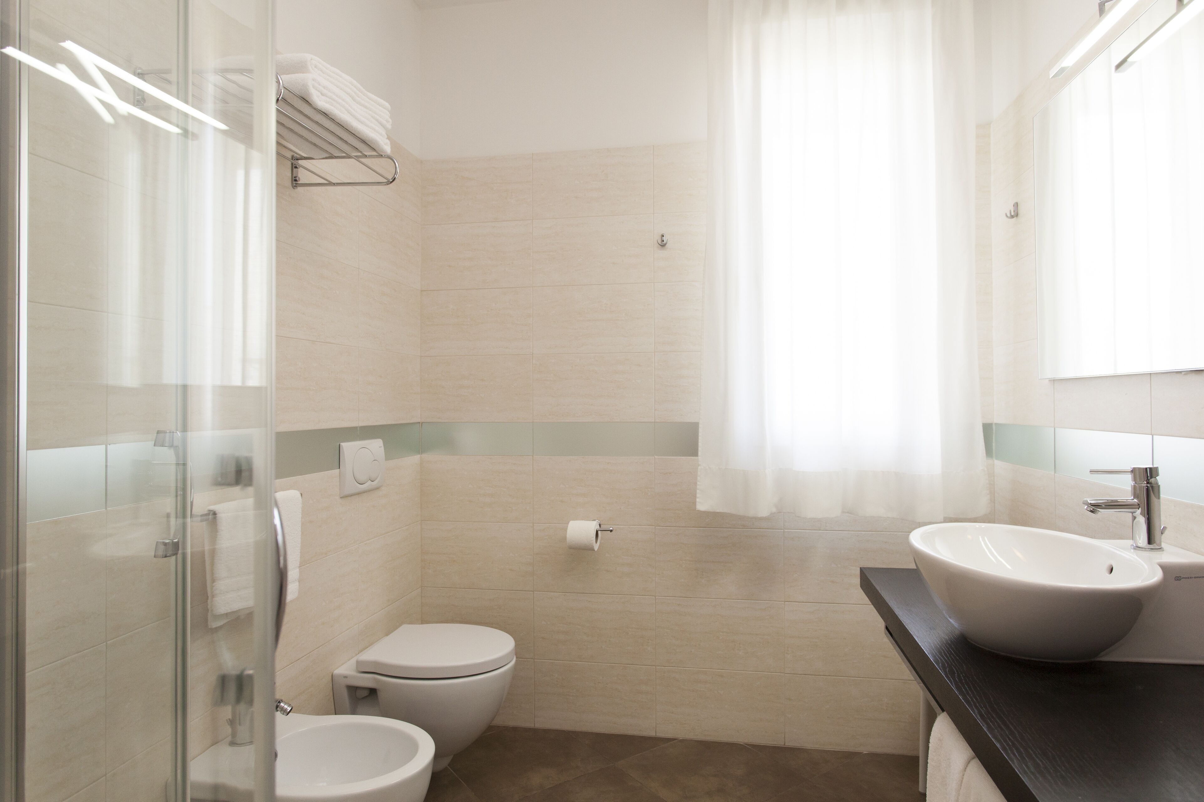 A modern bathroom with a glass shower enclosure, a toilet, a sink, and a mirror.