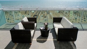 A balcony with wicker furniture and a view of the beach. - Hotel Orizzonte (Jesolo)