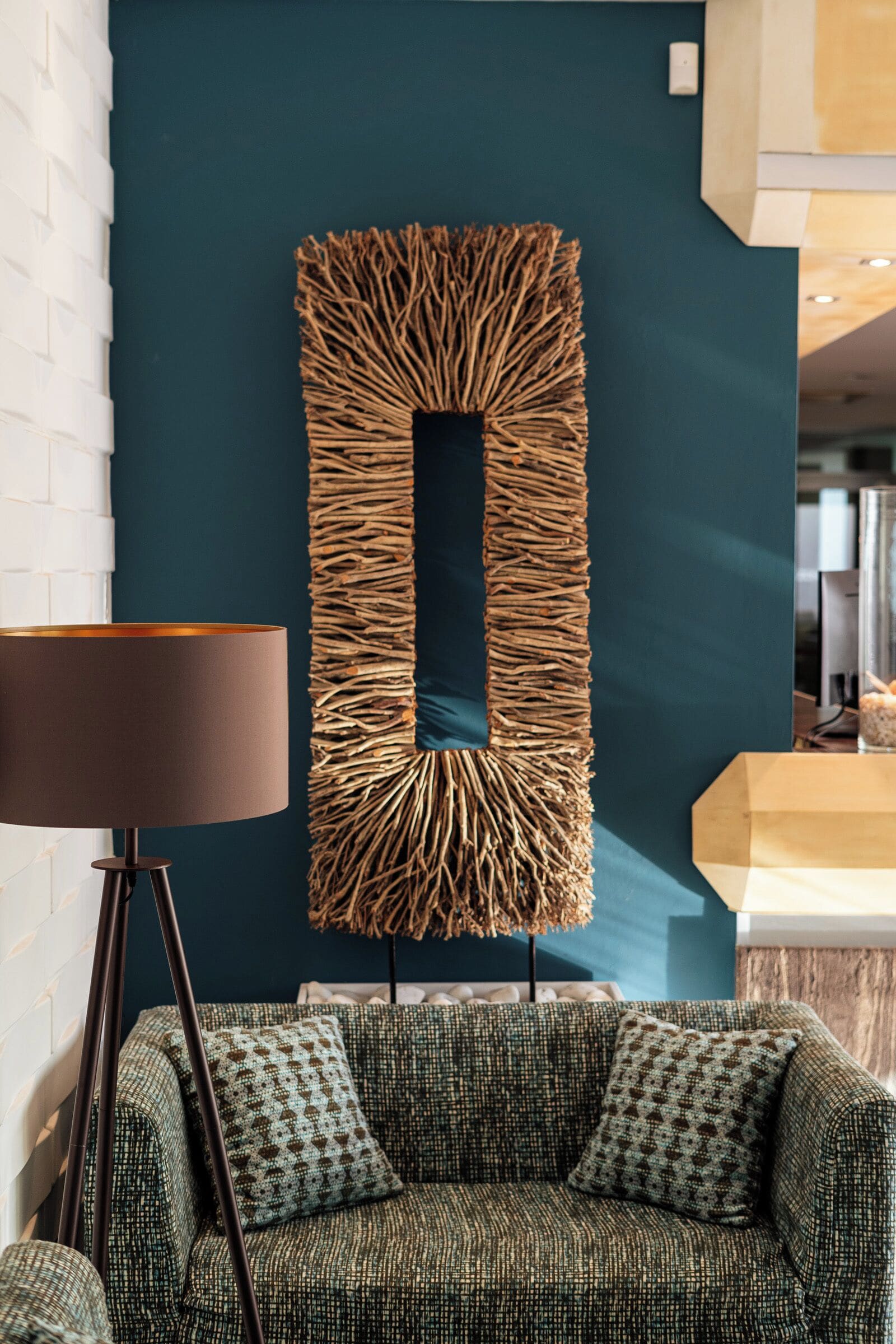 A modern living room with a textured wall art piece, a patterned sofa, and a floor lamp.