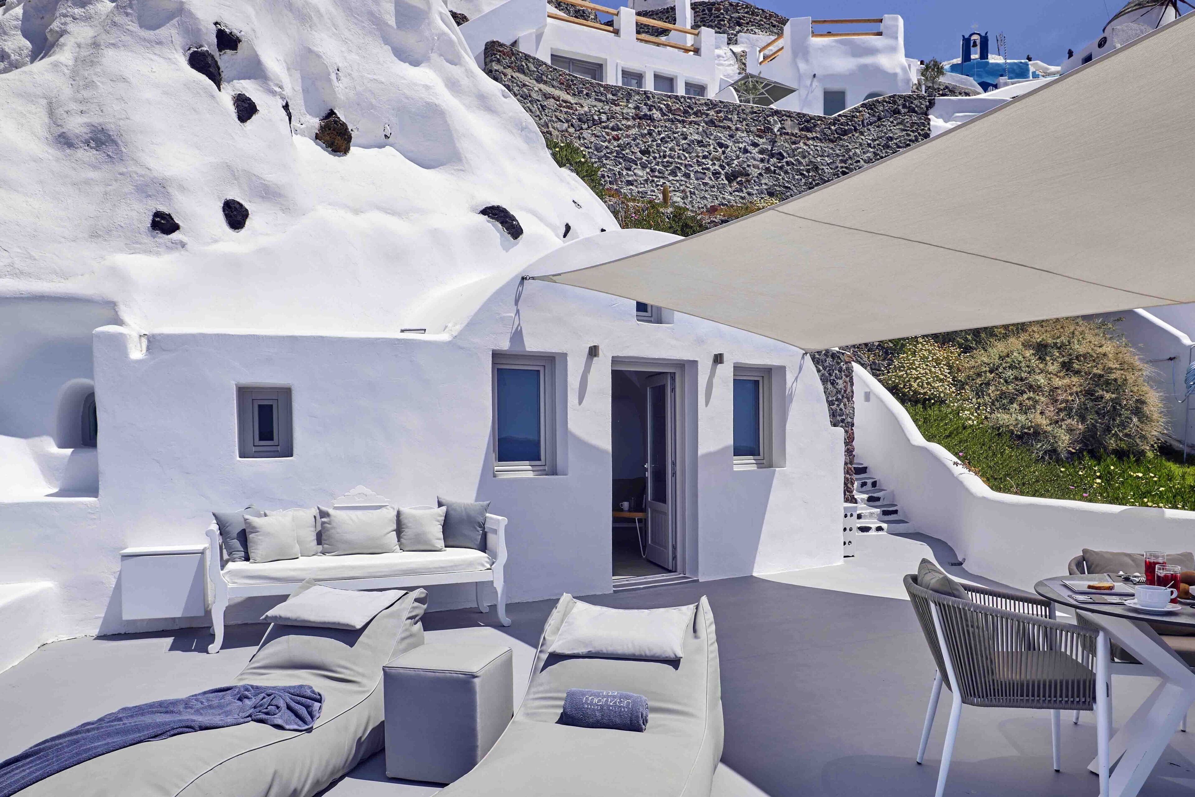 A modern outdoor lounge area with white walls and a stone staircase.