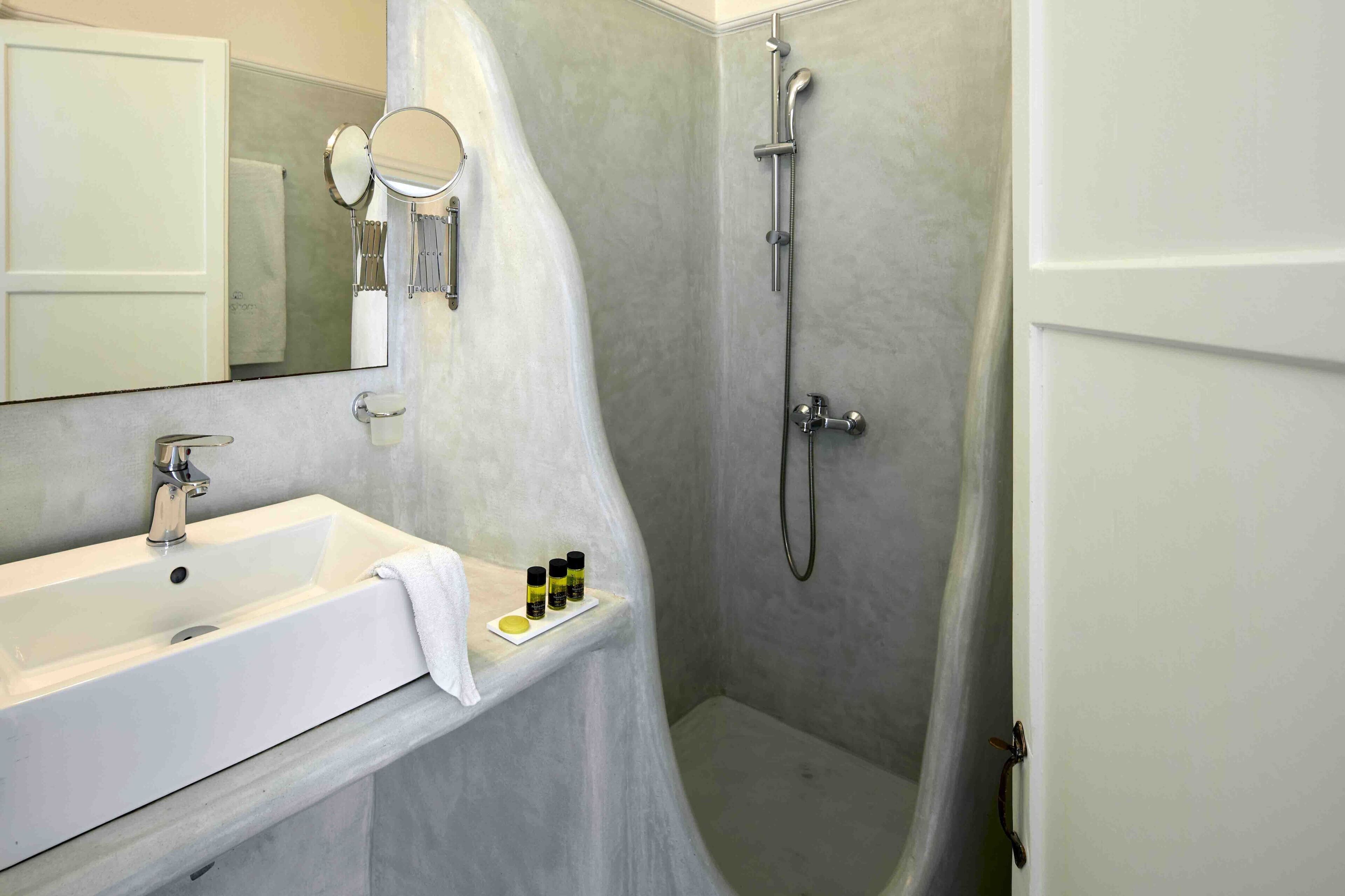 A bathroom with a white sink, a mirror, and a shower.