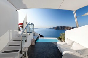Un balcon extérieur moderne avec une piscine, des meubles blancs et une vue sur la mer.