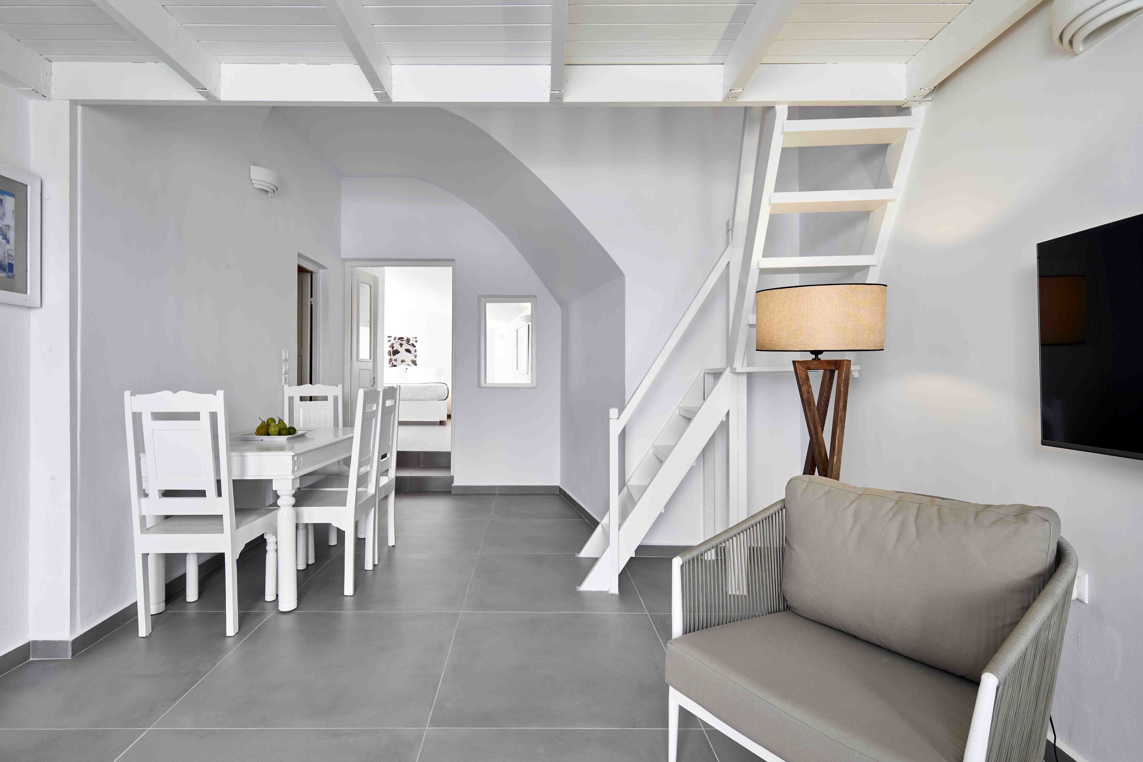 A modern interior with a dining area, a sofa, and a staircase.