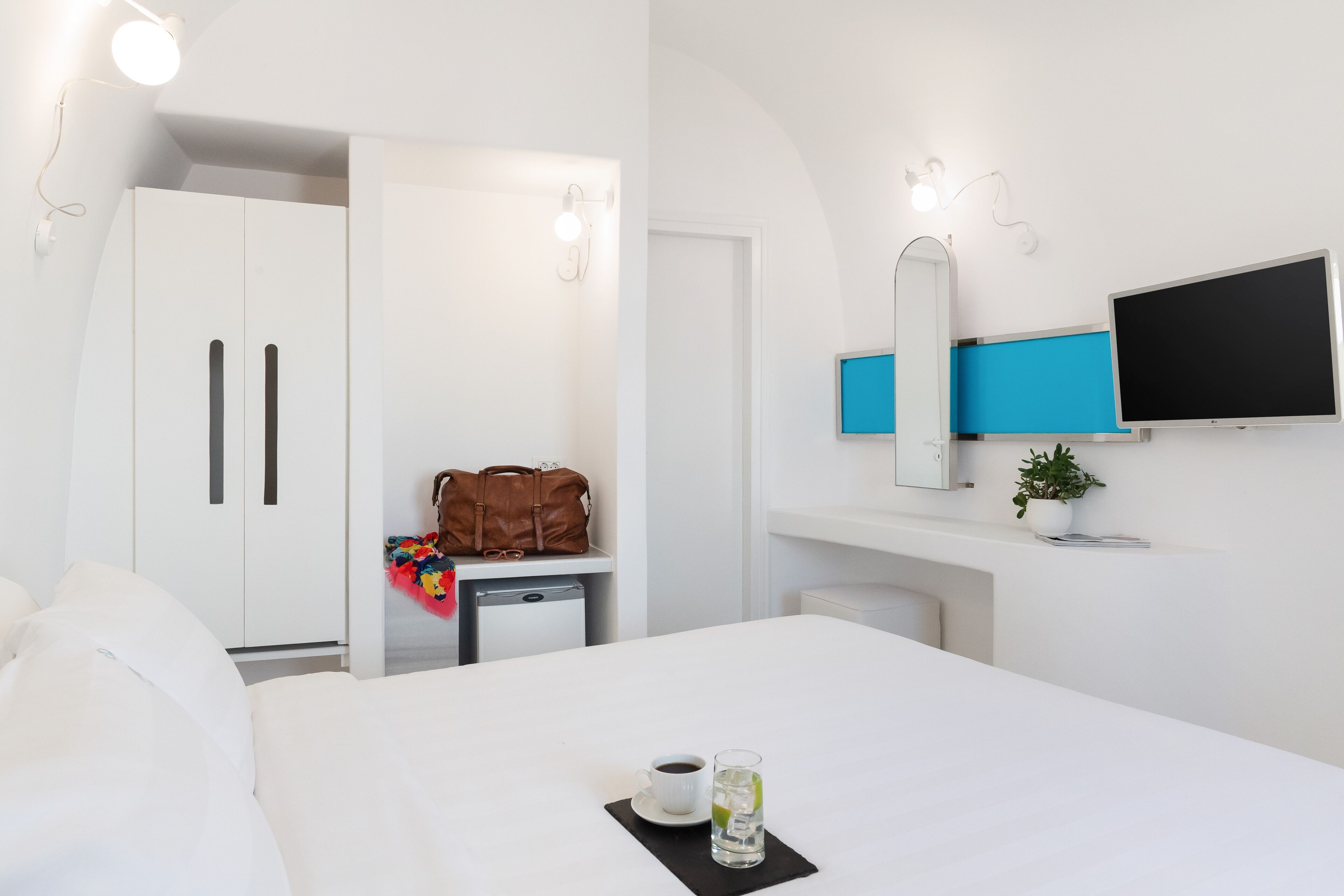 A hotel room with a bed, a desk, a TV, a wardrobe, and a bathroom.