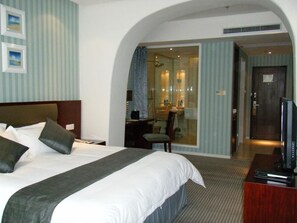 A hotel room with a large bed, a desk, a television, and a bathroom visible through an arched doorway. - Rhea Boutique Hotel @ Shanghai Railway Station (Shanghai)