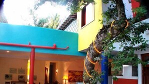 A cozy interior with a dining area, a staircase, and a tree with orange lights. - Aos Sinos dos Anjos Art Hotel (Arraial d'Ajuda)