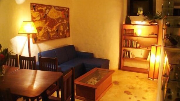 A cozy living room with a blue sofa, a wooden coffee table, and a bookshelf. - Aos Sinos dos Anjos Art Hotel (Arraial d'Ajuda)