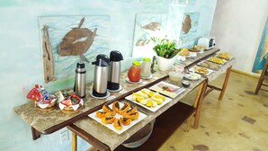 A buffet table with various food items and condiments, including sliced fruits, sandwiches, and a thermos. - Aos Sinos dos Anjos Art Hotel (Arraial d'Ajuda)