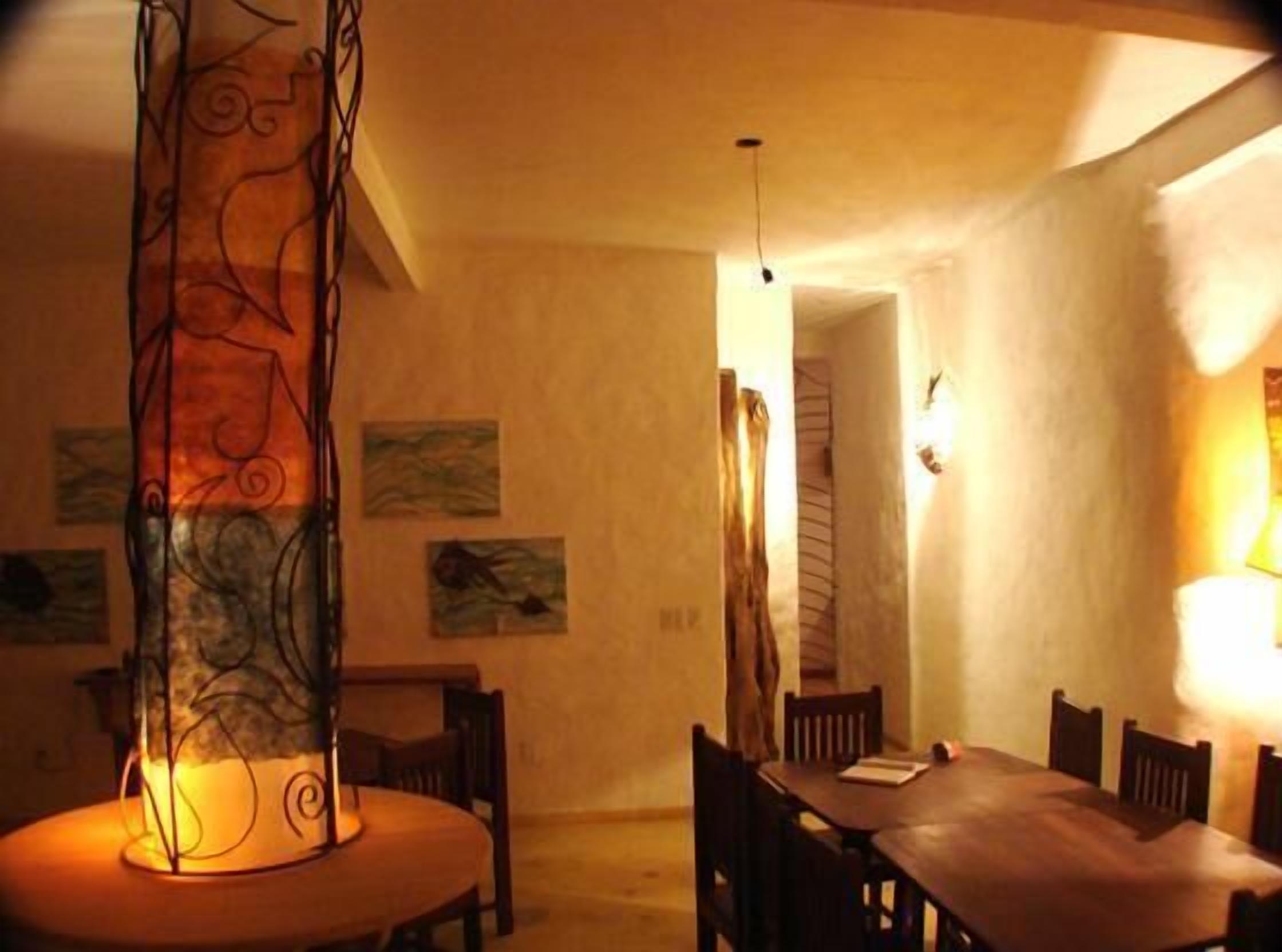 Un coin repas avec une table et des chaises en bois, un luminaire suspendu et deux tableaux accrochés au mur.