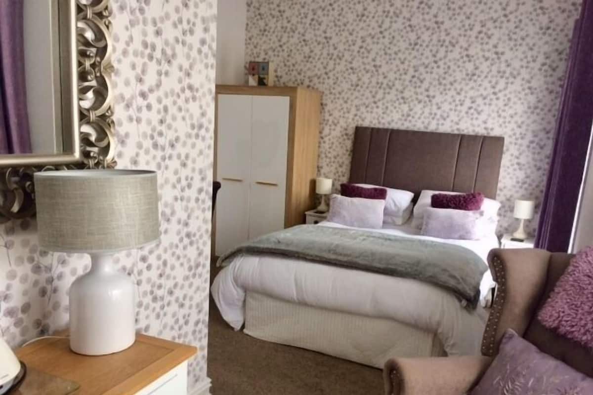 A bedroom with a bed, bedside tables, a wardrobe, and a mirror.