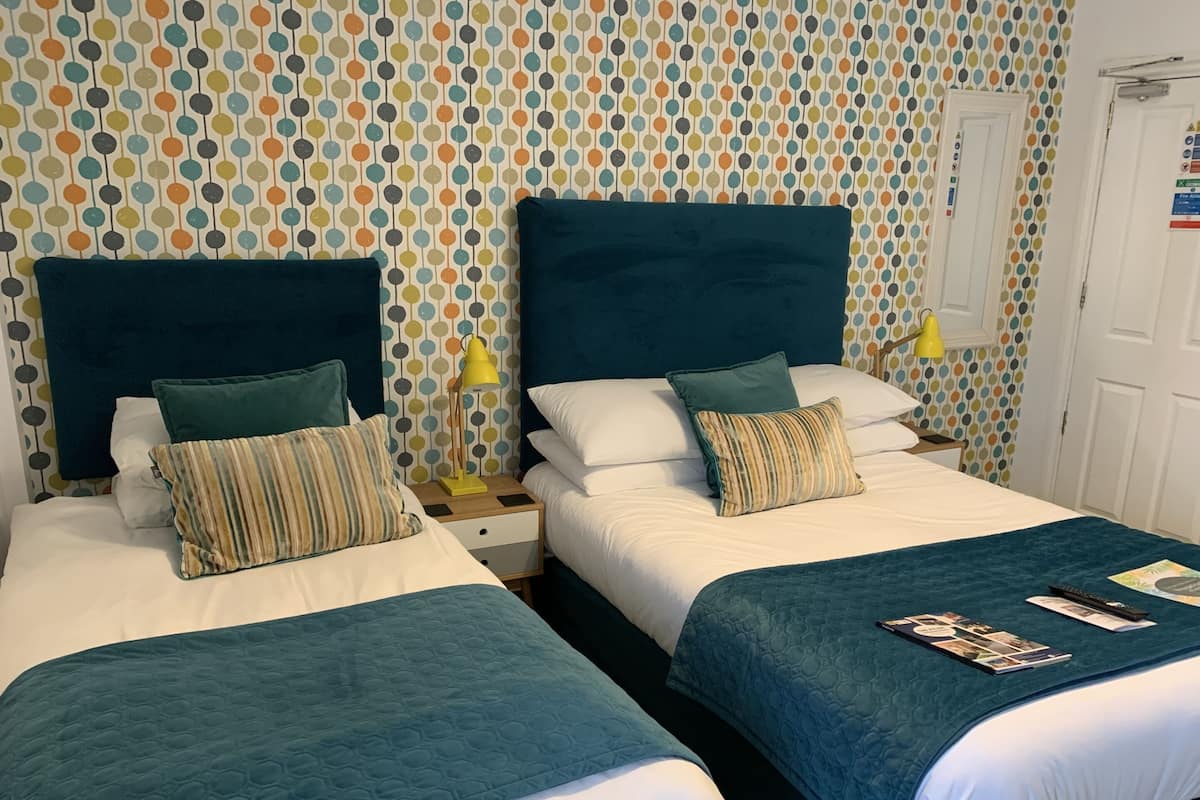 Two single beds with dark headboards, white bedding, and striped pillows.