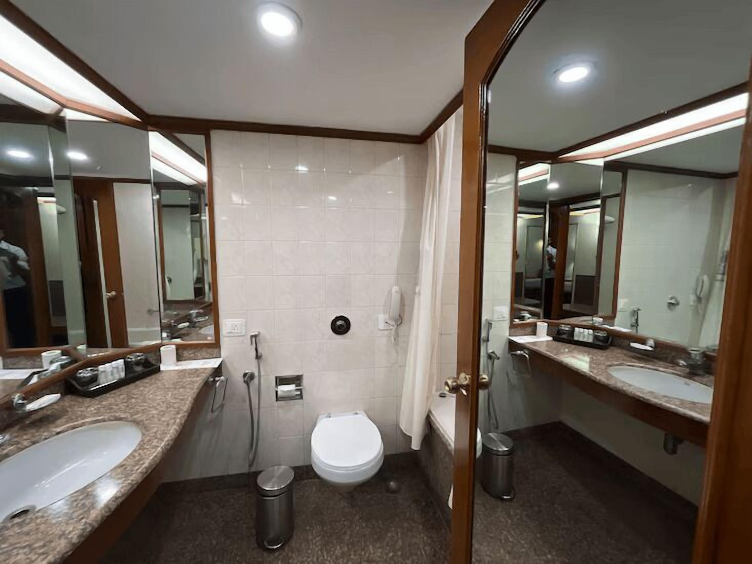 Een moderne badkamer met toilet, hygiëneslot en twee wasbakken.
