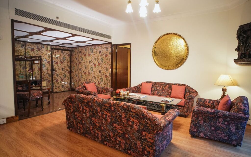 A room with a sofa set, a round decorative wall piece, and a traditional-style mirror.