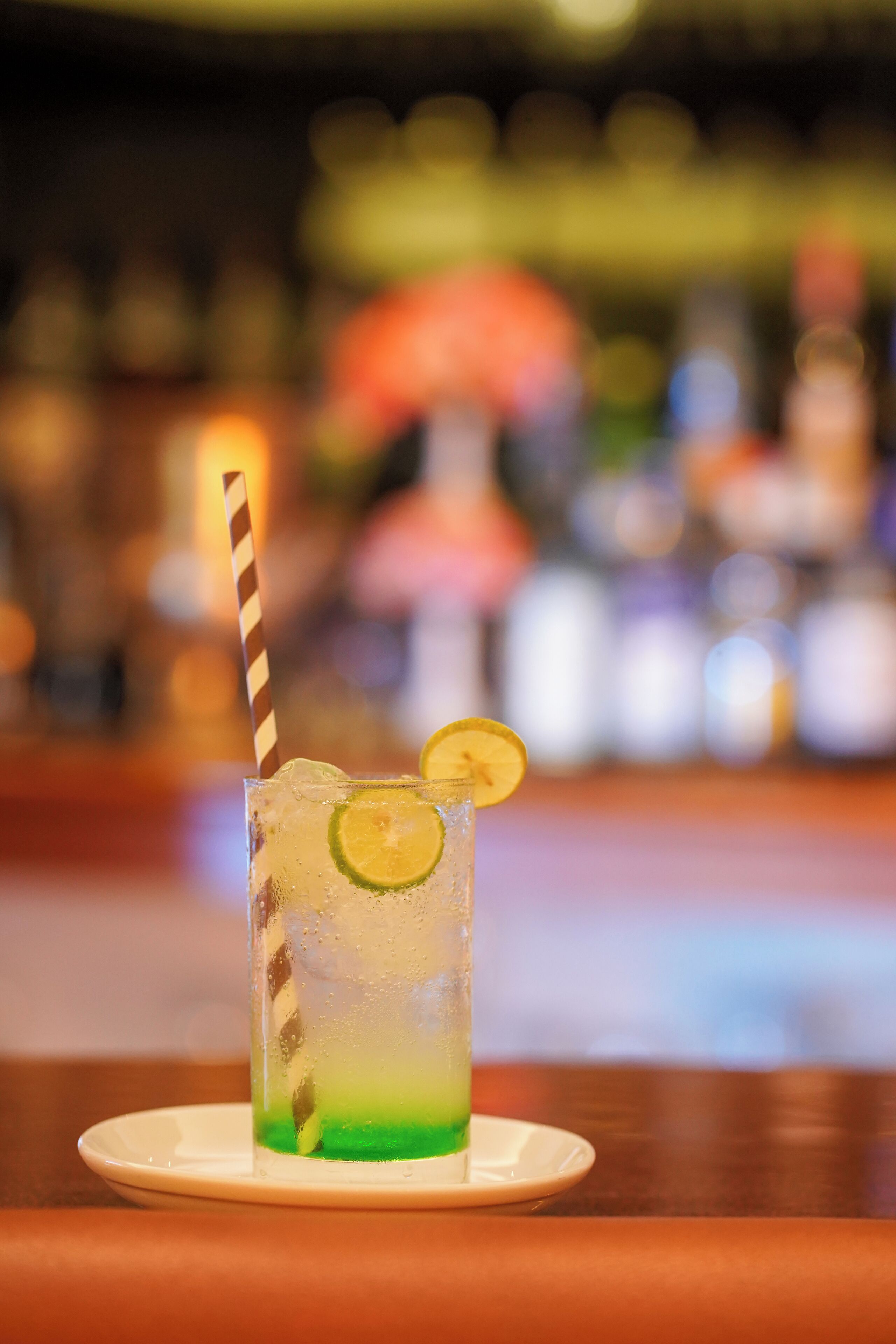 A bar setting with a glass of cocktail on a coaster.