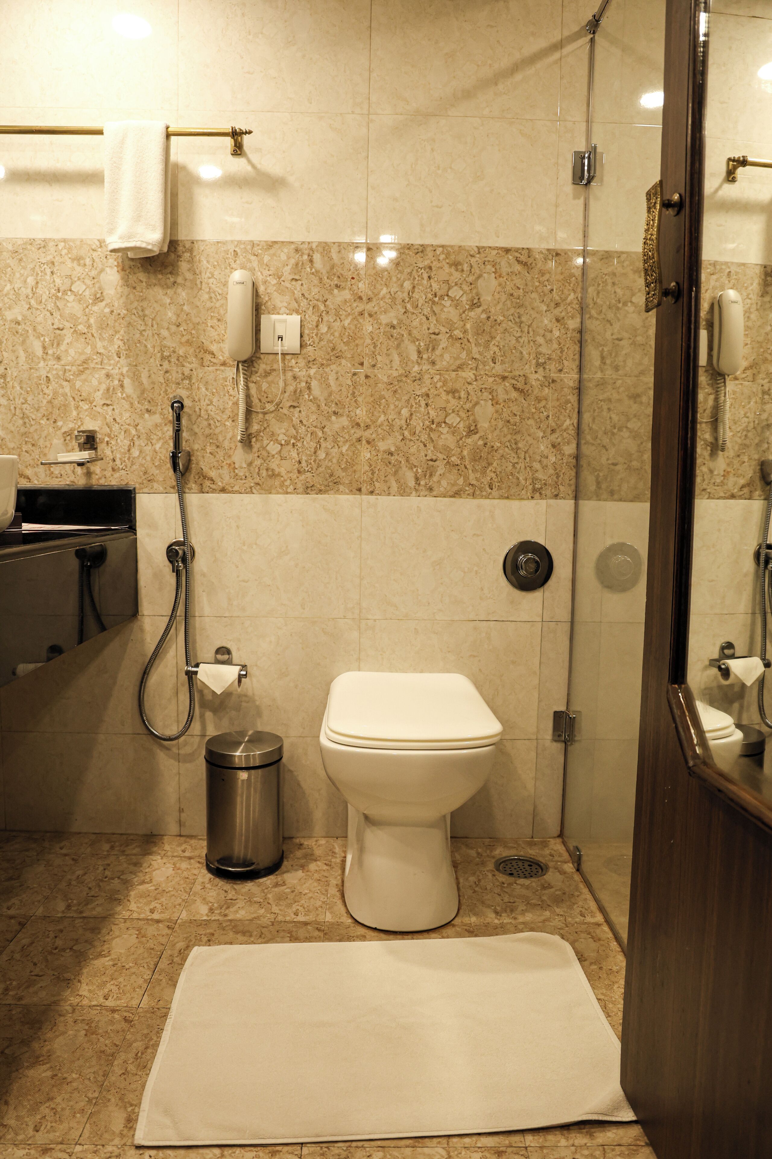 A bathroom with a toilet, a shower, a towel rack, and a trash can.