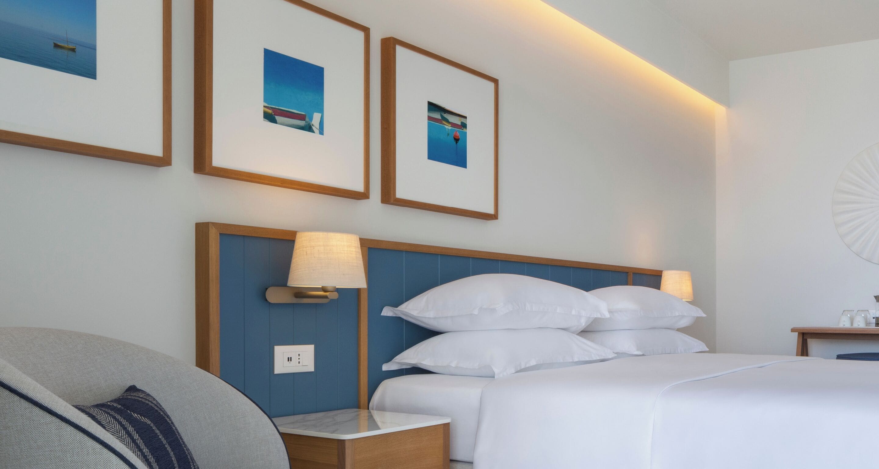 A hotel room with a bed, two bedside lamps, a nightstand, and framed pictures on the wall.
