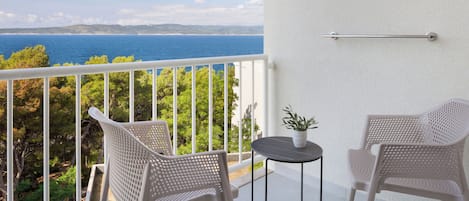 A balcony with two wicker chairs, a small round table, and a potted plant.