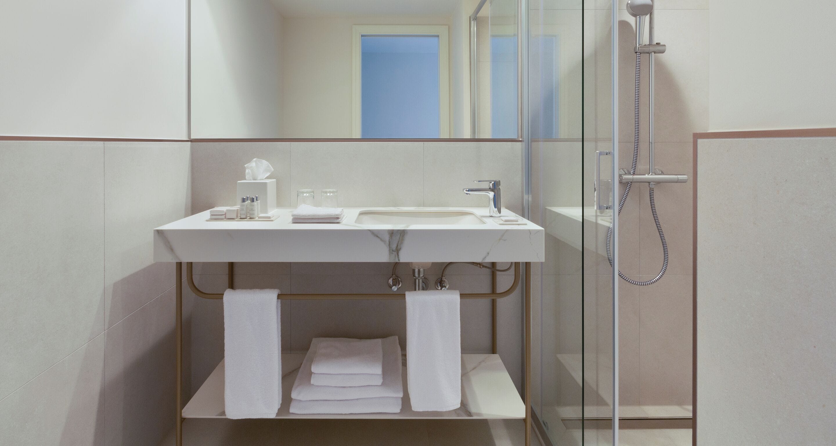 A modern bathroom with a glass-enclosed shower, a white sink, and neatly folded towels.