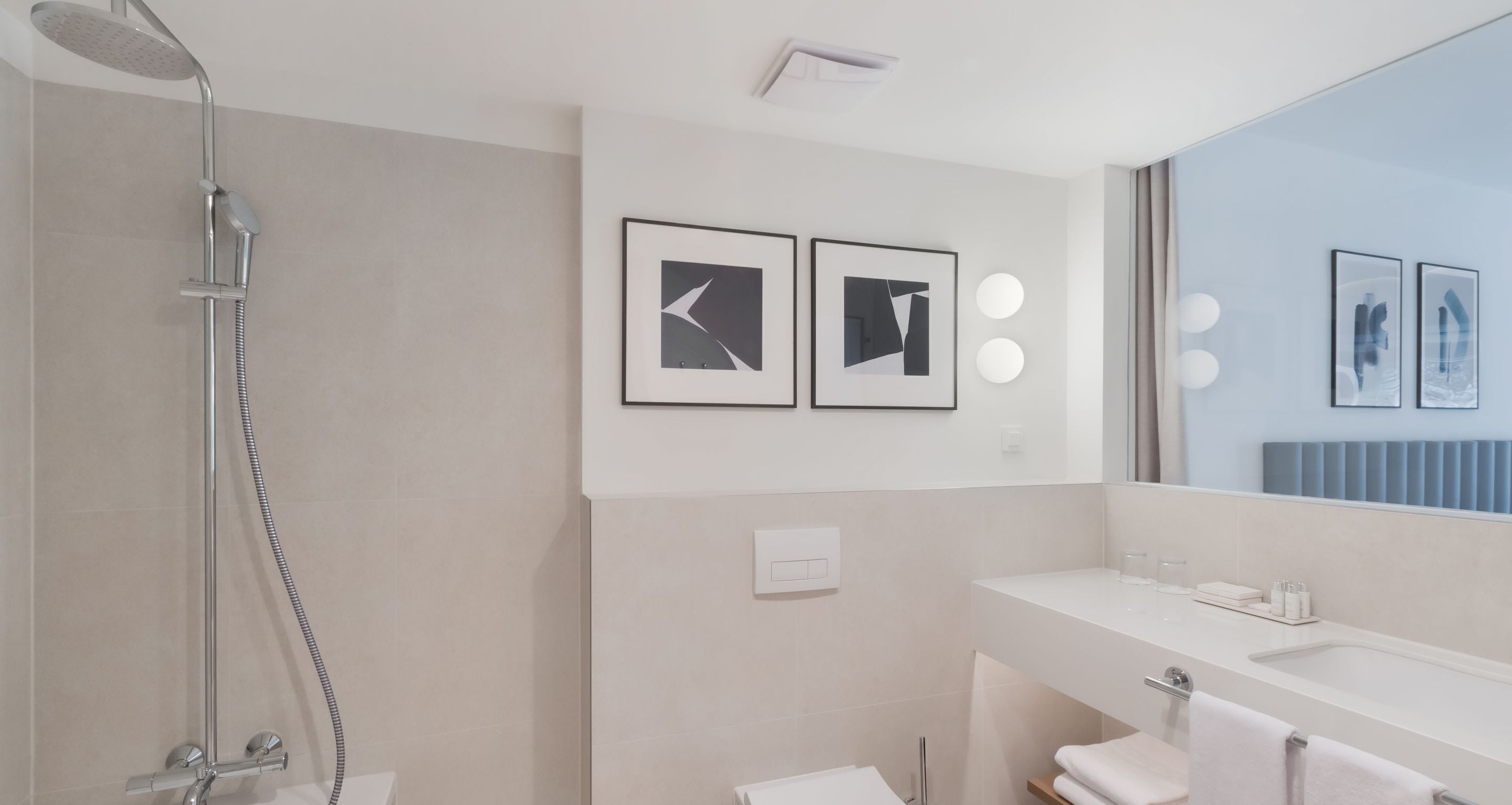 Ein modernes Badezimmer mit Dusche, Waschbecken und zwei gerahmten Bildern an der Wand.