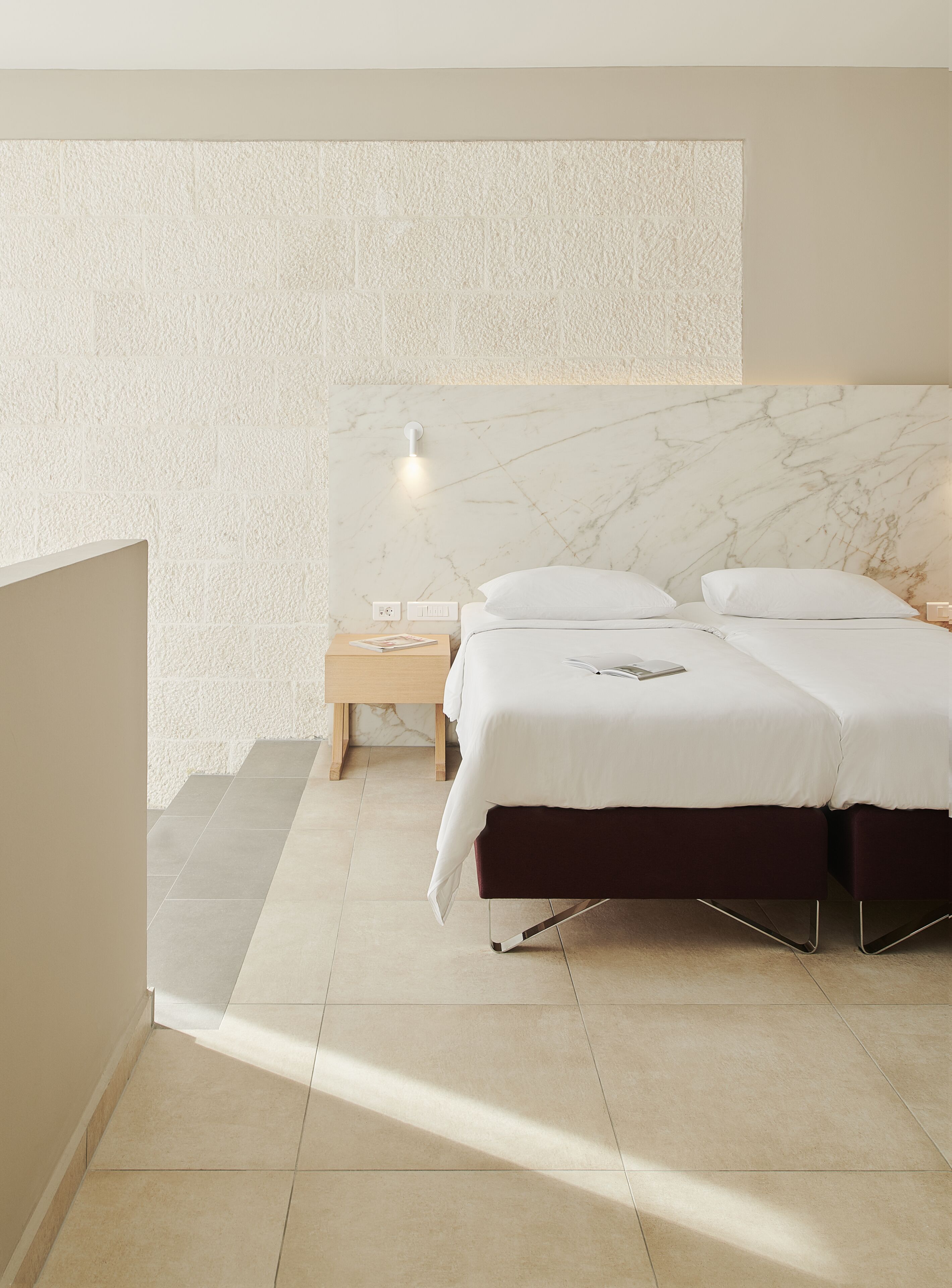 A bedroom with a bed, bedside table, and a wall-mounted light fixture.