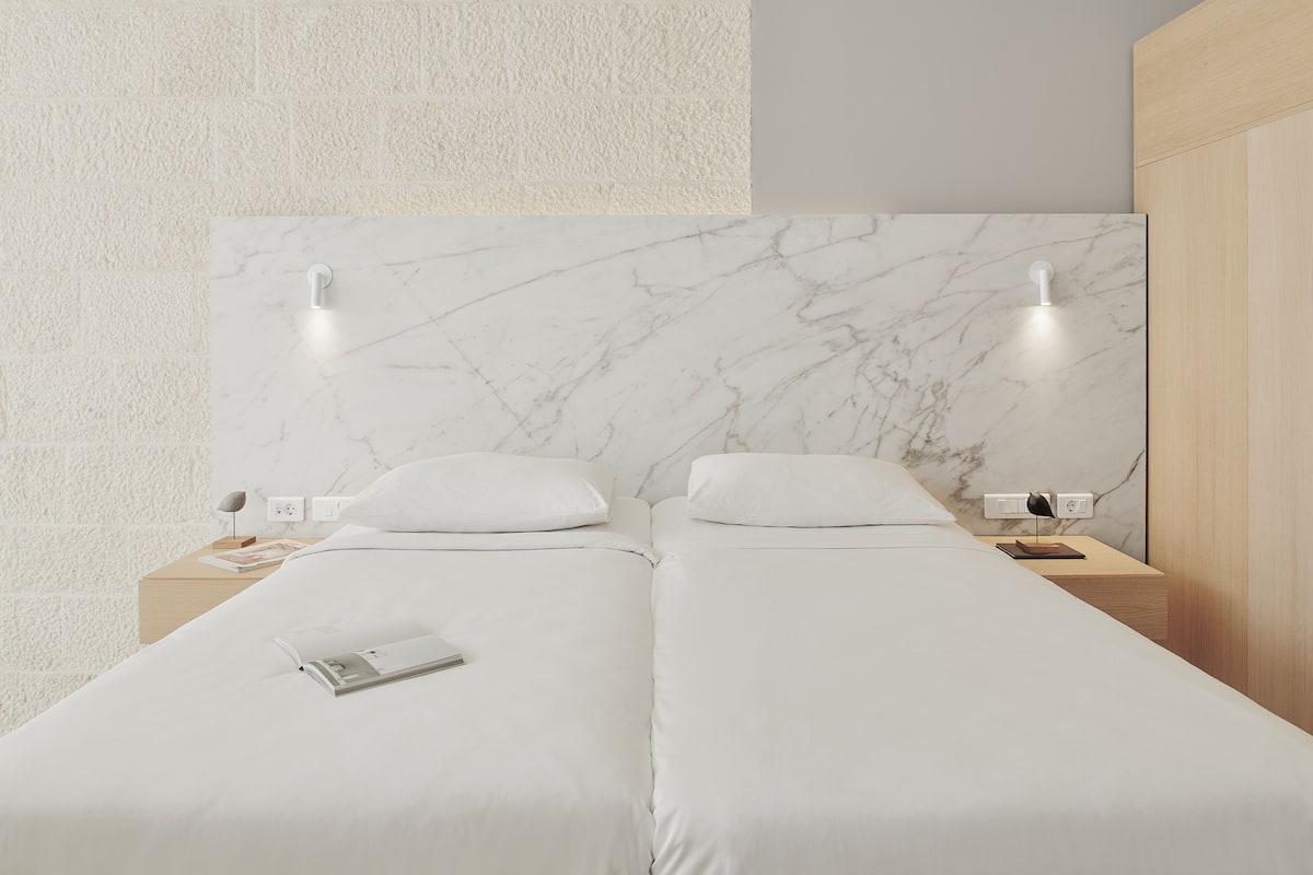 A double bed with white bedding, two bedside tables, and a marble headboard.