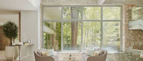 A spacious living room with a large window, a stone wall, and a modern sofa set.