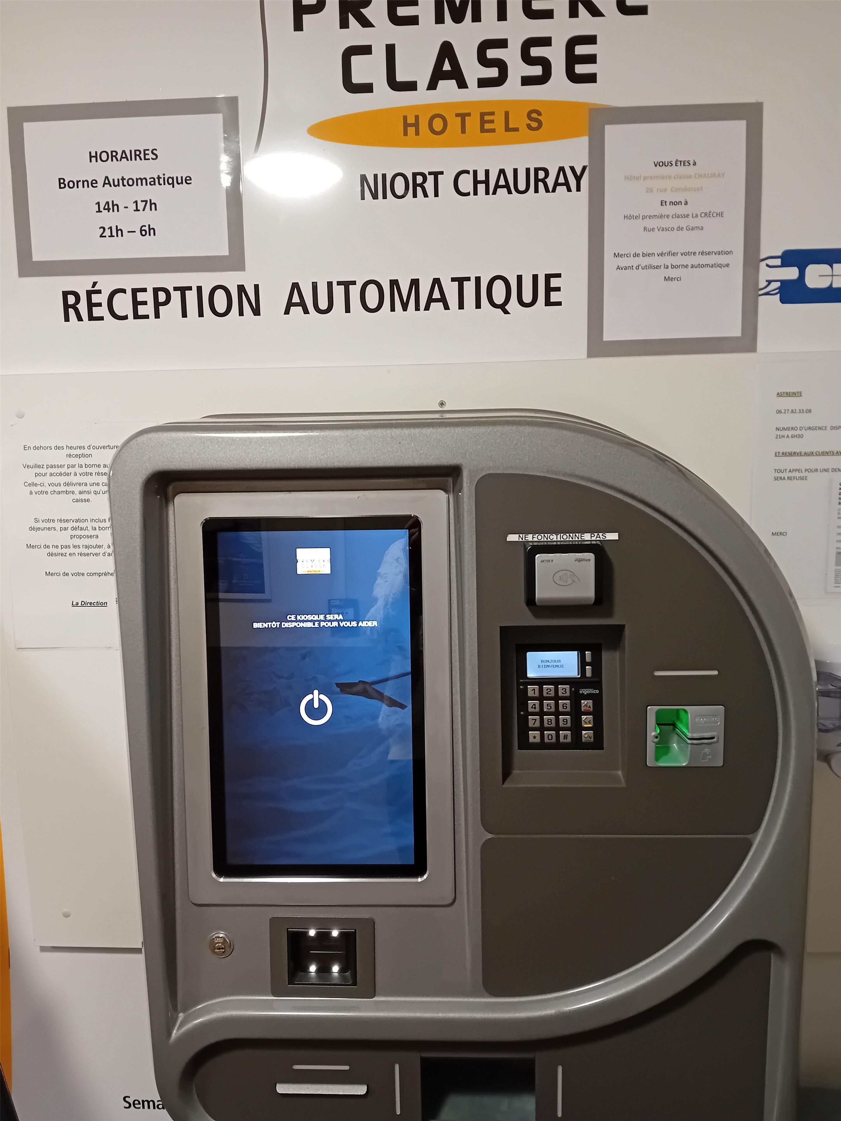 An automated reception kiosk with a screen displaying a power symbol, a keypad, and a card slot.