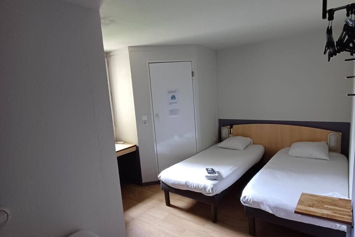 A room with two single beds, a desk, and a wardrobe.