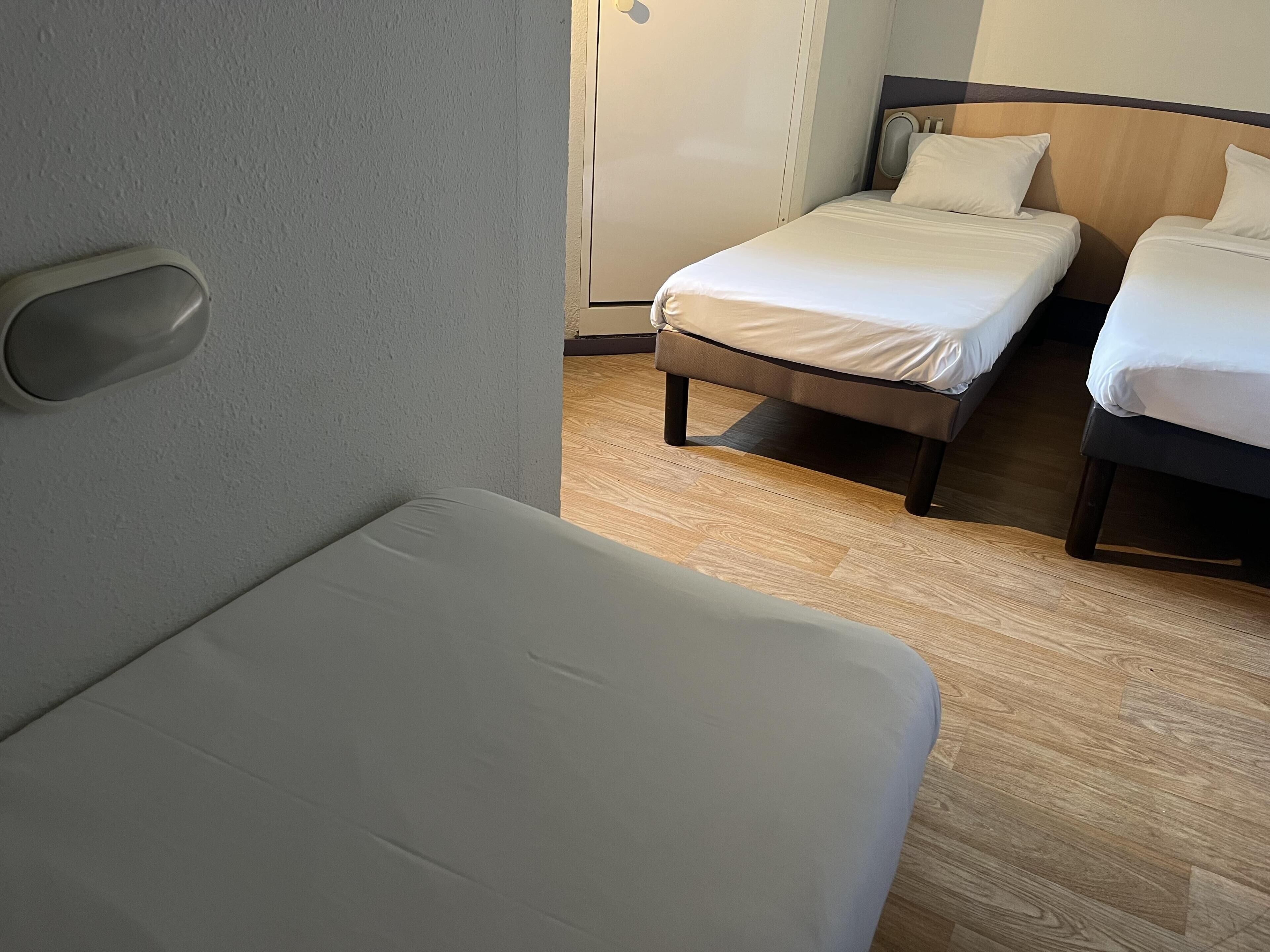 A hotel room with a single bed, a smaller bed, and a sofa.