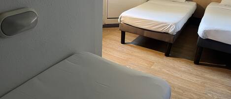 A hotel room with a single bed, a smaller bed, and a sofa.