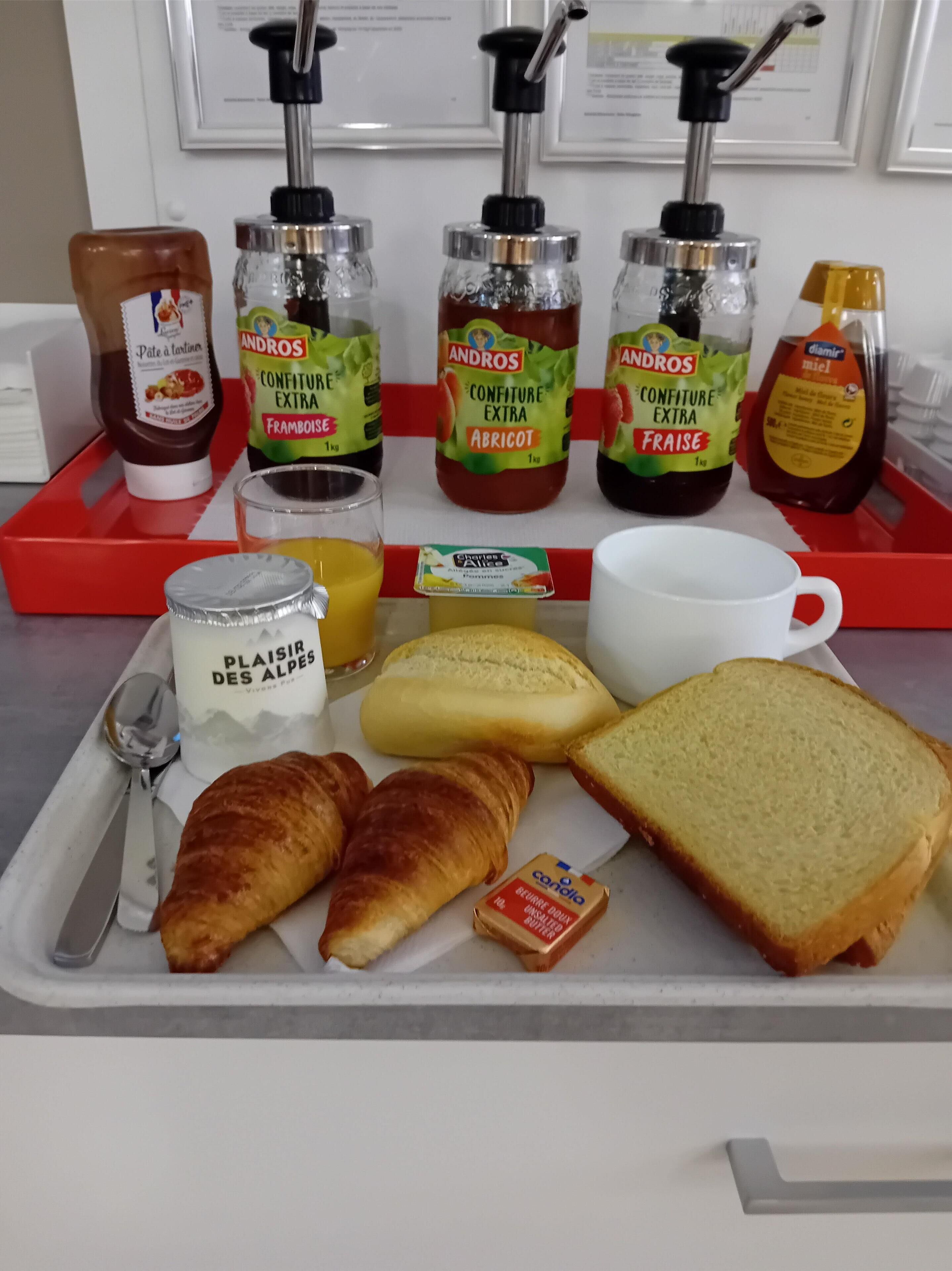 A breakfast tray with condiments, bread, butter, and a drink.