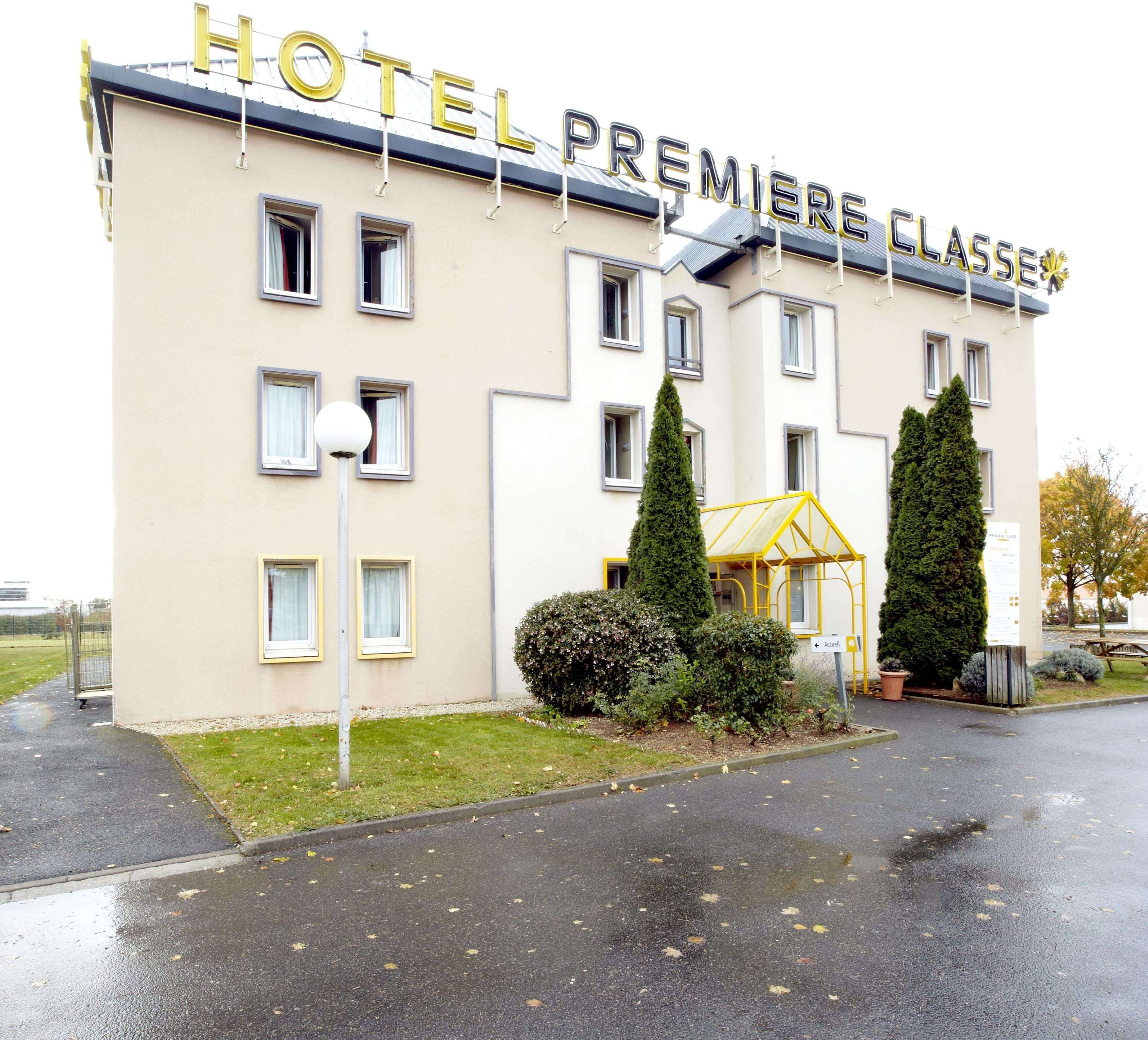 A hotel named "HOTEL PREMIERE CLASSE" with a modern facade, multiple windows, and a well-maintained lawn area.